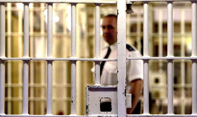 A prison guard at HMP (Her Majesty's Prison) Pentonville stands behind a locked gate May 19, 2003 in London. 