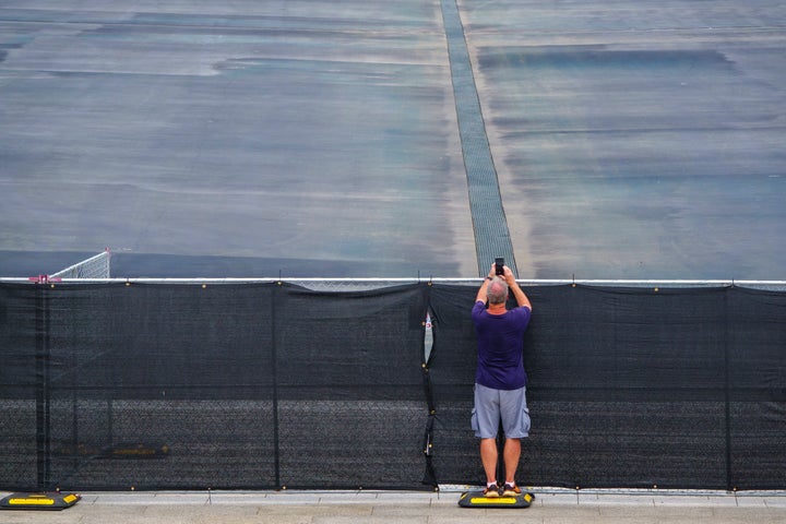 A visitor stands on a temporary fencing weight to take a photo of the recently drained Lincoln Memorial Reflecting Pool back in August.