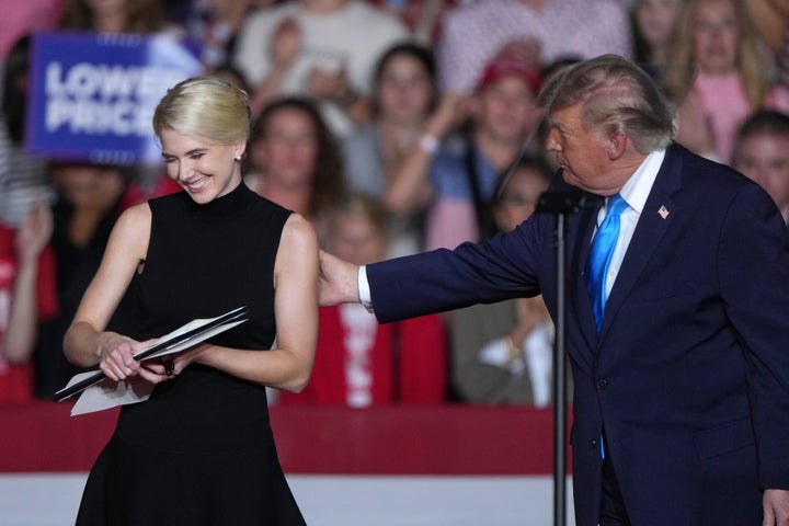 President Donald Trump pats aide Natalie Harp on the shoulder after handing her an executive order he signed at a campaign rally in Grand Island, Neb. on Oct. 5, 2026.