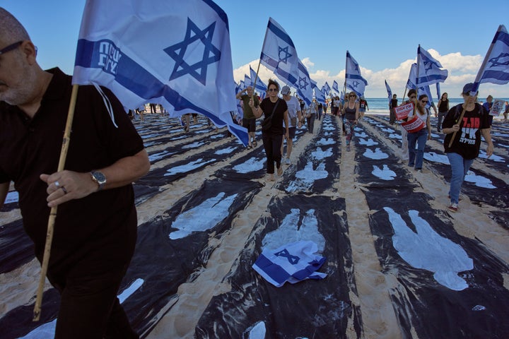 People carrying Israeli flags walk through an installation marking the third anniversary of the Oct. 7, 2023, Hamas-led attack on Israel, on the beachfront in Tel Aviv, Israel, Wednesday, Oct. 7, 2026. (AP Photo/Oded Balilty)