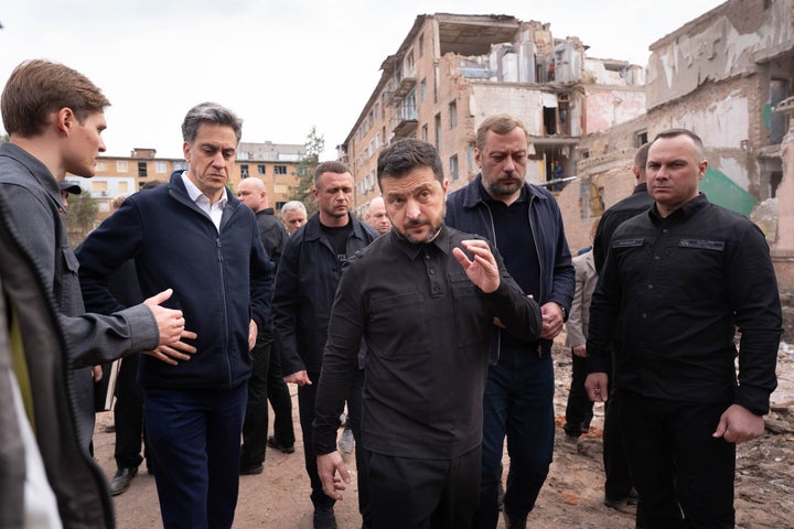 U.K. Foreign Secretary Ed Miliband (second left) and Ukrainian President Volodymyr Zelensky (center) visit on Oct. 8, 2026, the site of a Russian missile strike that hit a residential area in northern Ukraine’s Pryluky, where 22 people, including five children, were killed two days earlier.