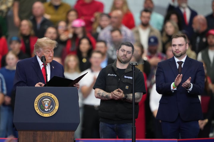 President Donald Trump prepares to sign pardons Tuesday for Zachary Czubak and Patrick Fleming, right, at a campaign rally at the Curtis D. Menard Memorial Sports Center in Wasilla, Alaska. 
