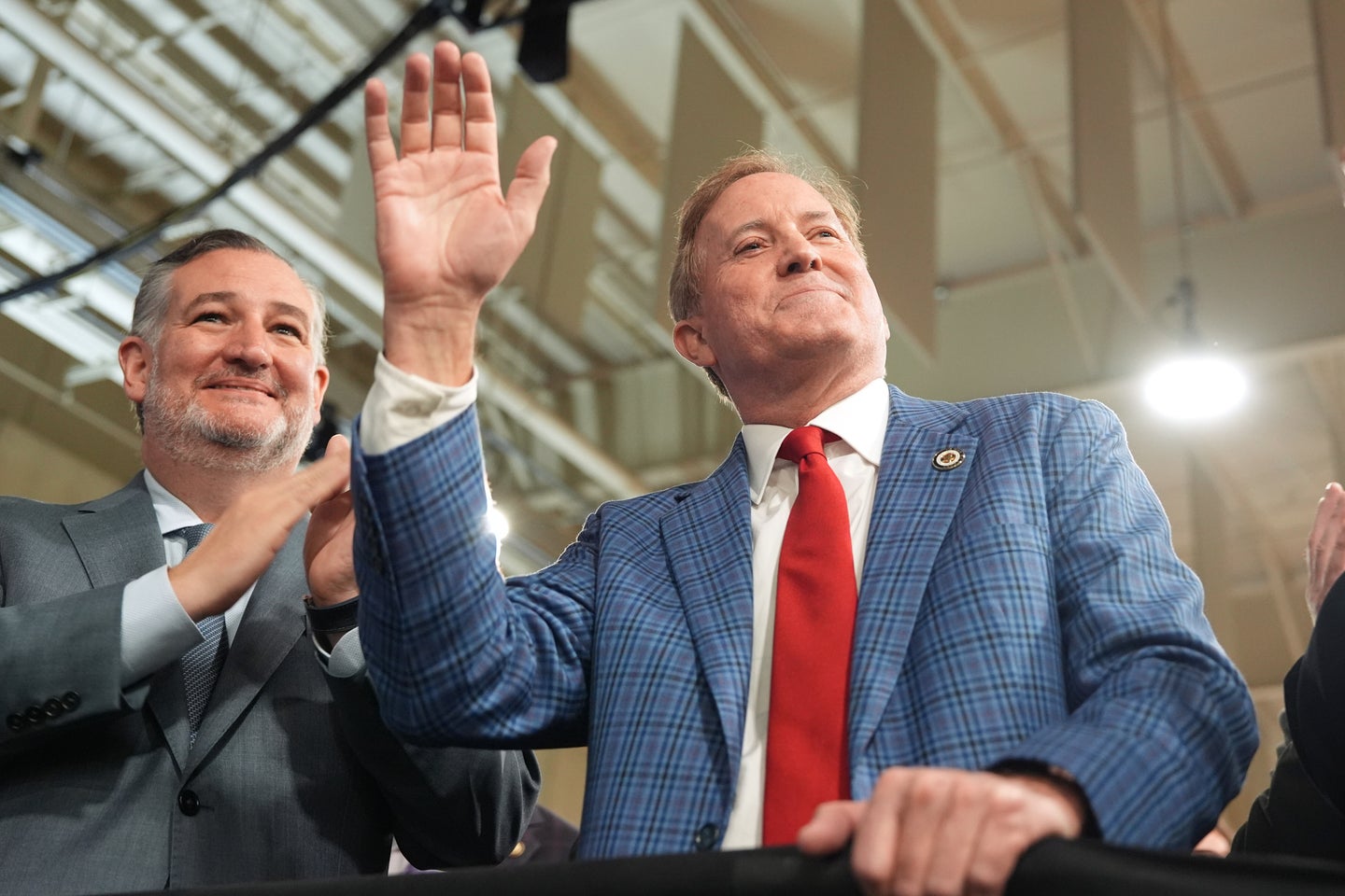 Sen. Ted Cruz (left) applauds as Texas Attorney General Ken Paxton (right) waves during President Donald Trump’s speech at Peterbilt Motors earlier this month i