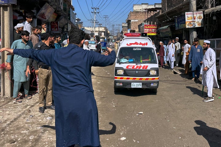 A volunteer clears the way for an ambulance transporting injured school children following a roof collapse at a private school in Peshawar, Pakistan, on Oct. 15, 2026.