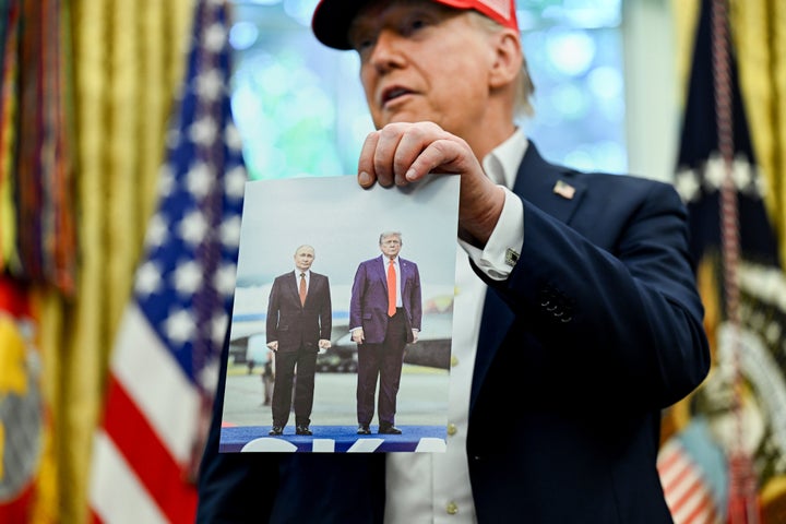 President Donald Trump holds a photo of himself with Russian President Vladimir Putin in Alaska while speaking last year in the Oval Office of the White House.