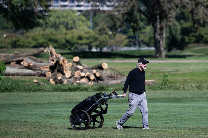 A golfer walks on the course in front of cut down trees at East Potomac Golf Links on Monday.