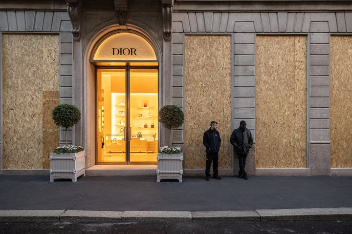 Two private security guards stand in front of the windows of the French multinational luxury fashion house Christian Dior, boarded-up with plywood panels to guard against looting and vandalism ahead of potential unrest, on October 24, 2026 in via Monte Napoleone, Milan, Italy. (Photo by Emanuele Cremaschi/Getty Images)