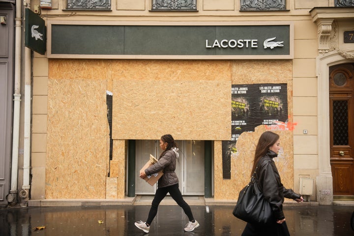 Passersby walk past a boarded-up store on the eve of a demonstration against rising living costs in Paris, Friday, Oct. 23, 2026. (AP Photo/Teresa Suarez)
