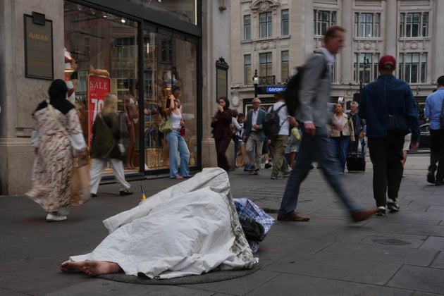 A homeless man sleeps on a street in a shopping district in central London, Wednesday, Aug. 19, 2026. 