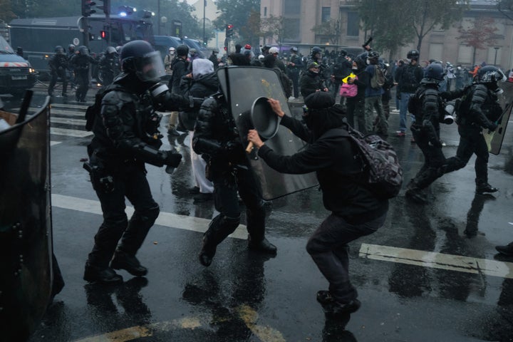 A protester defends himself against police officers wearing shields, helmets and body armor using a frying pan during an October 24 protest by the Yellow Vests, high school and university students, and trade unions, in Paris, France.
