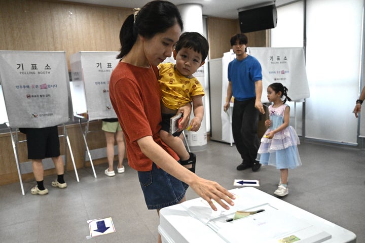 2026年6月3日に韓国で行われた統一地方選で、子どもを抱きながら一票を投じる有権者